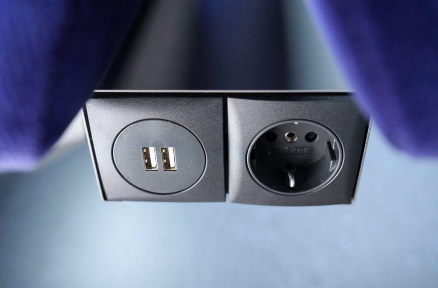 Das Foto zeigt Steckdosen und USB-Ladeplätze zwischen zwei Sitzen in einem Mireo-Zug.
