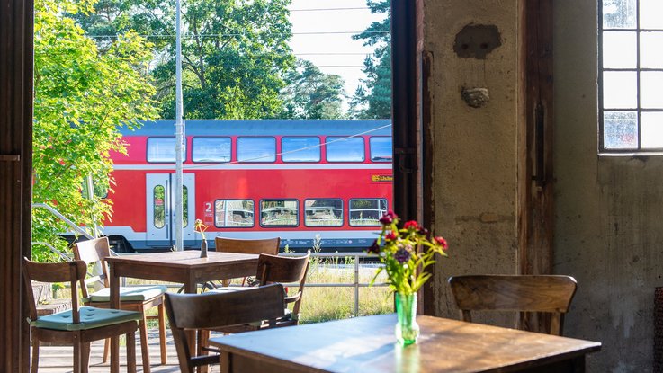 Ein Foto vom Bahnhofsgebäude in Klasdorf mit einem Zug der Deutschen Bahn im Hintergrund
