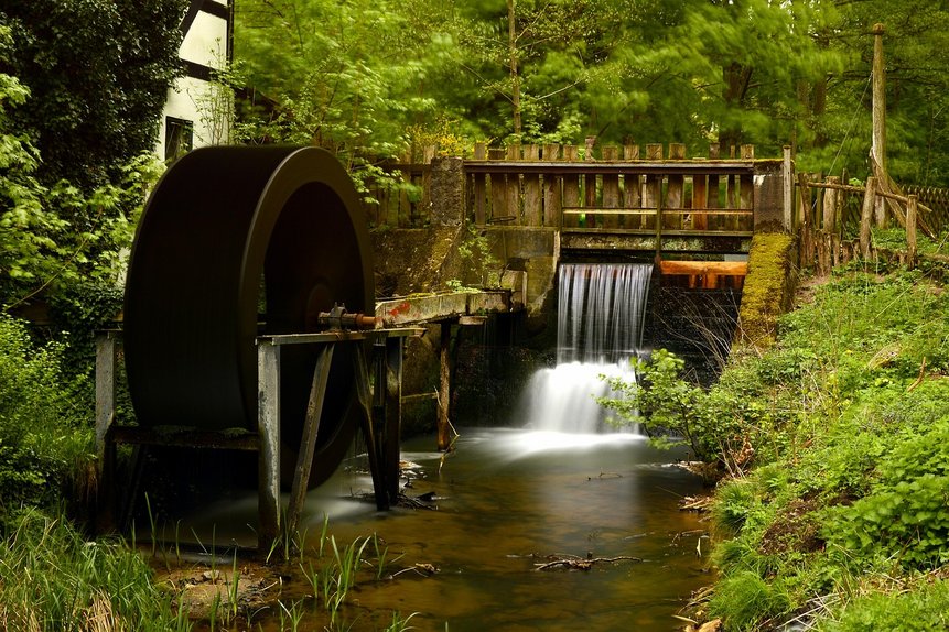 Das Foto zeigt eine Wassermühle mit Mühlrad und Wasser.