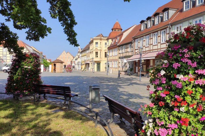 Das Foto zeigt im Vordergrund Sitzbänke und Blumen, im Hintergrund alte Fachwerkhäuser.