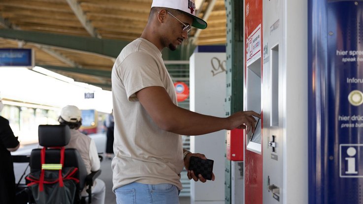 Mann kauft Ticket am Fahrkartenautomat
