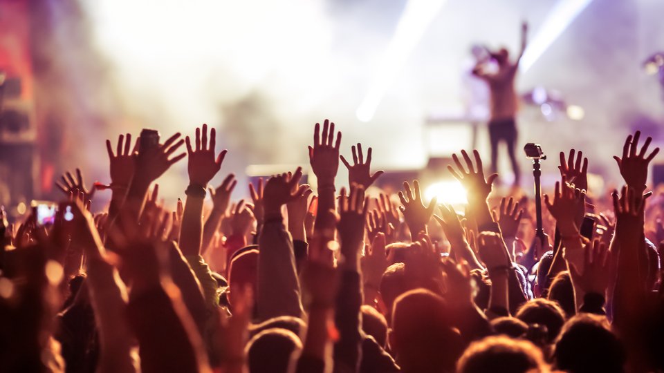 Eine Menge Menschen schauen auf eine Bühne auf einem Festival