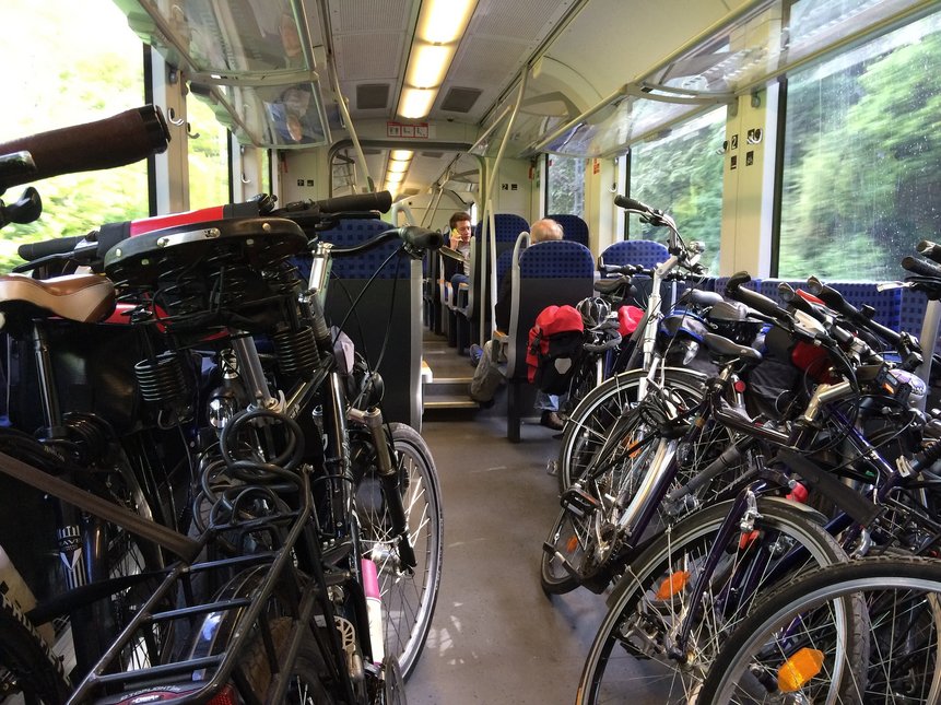 Mehrere Fahrräder in einem Zugabteil mit Personen in der Regionalbahn
