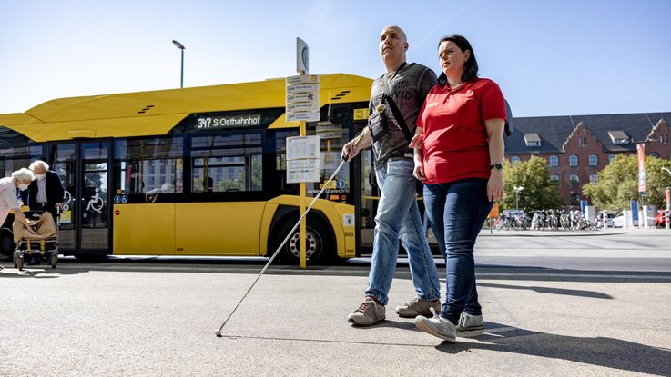 Seheingeschränkter Mann mit Servicebegleitung vor Bus