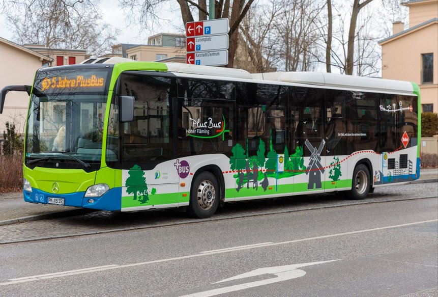 Ein PlusBus der Region Hoher Fläming an einer Haltestelle. Der Zielanzeiger zeigt 5 JAhre PlusBus.