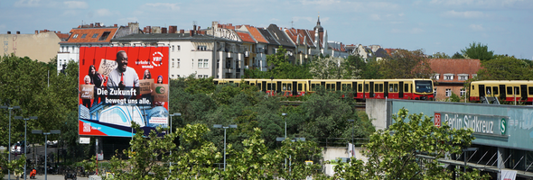 Blick auf den Bahnhof Südkreuz mit Vorplatz und vorbeifahrenden S-Bahn-Zügen