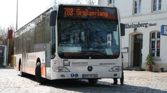 Das Bild zeigt einen Bus vor dem Bahnhofsgebäude in Rheinsberg.