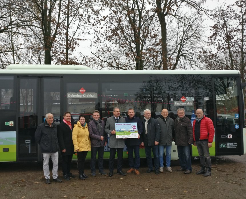 Bild zeigt Personen mit Pressetafel vor beklebtem PlusBus