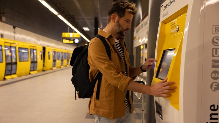 Mann kauft Fahrkarte am Fahrkartenautomat der BVG
