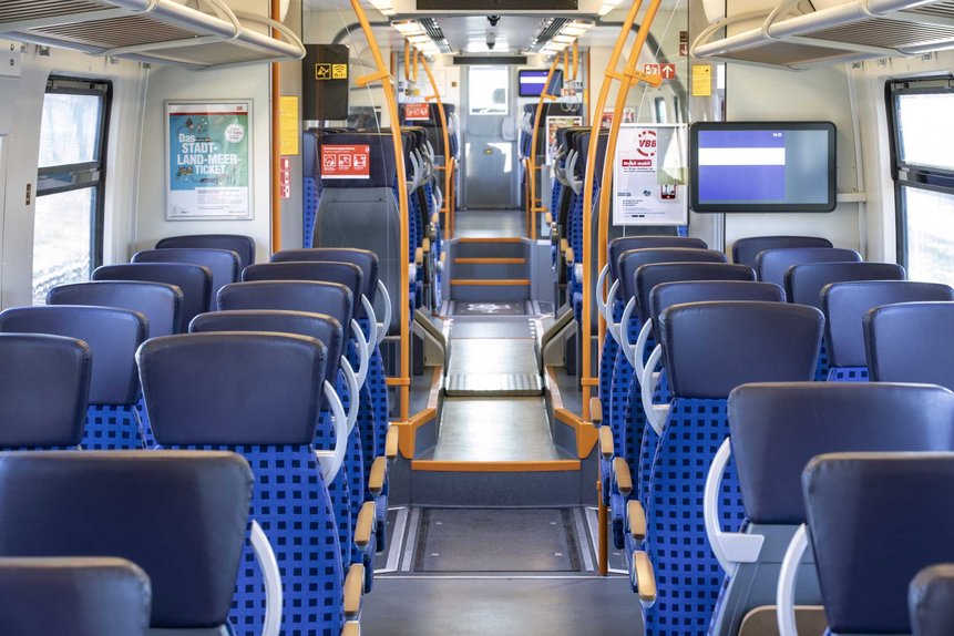 Das Foto zeigt die neue Innenraumgestaltung in der 2. Wagenklasse mit größeren Fahrgastinformation-Bildschirmen in einem modernisierten Talent2-Zug.
