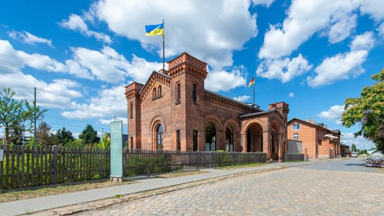 Das Foto zeigt den Vorplatz und das Bahnhofsgebäude von Halbe.