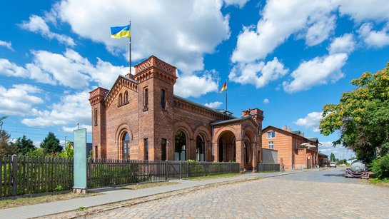 Das Foto zeigt den Vorplatz und das Bahnhofsgebäude von Halbe.