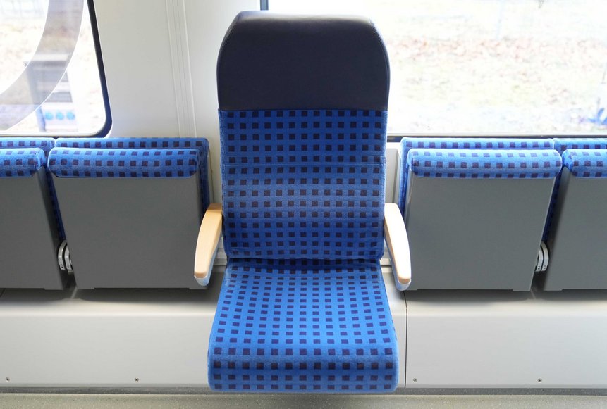 Das Foto zeigt Klappsitze mit und ohne Rücken- und Kopflehne im barrierefreien Wagen eines modernisierten Doppelstockwagens.