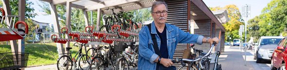 Mann mit Fahrrad an Fahrradabstellanlage
