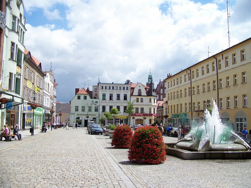 Marktplatz in Żary. Im Vordergrund sind große Blumenkasten und ein Springbrunnen zu sehen.