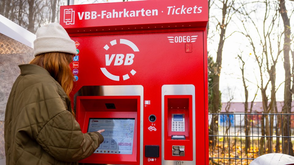 Ein Fahrgast, der vor einem roten VBB-Fahrkartenautomaten steht