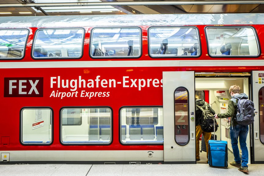 Flughafen-Express "FEX" Das Foto zeigt Personen mit Gepäck, die in einen Zug zum Flughafen BER einsteigen.