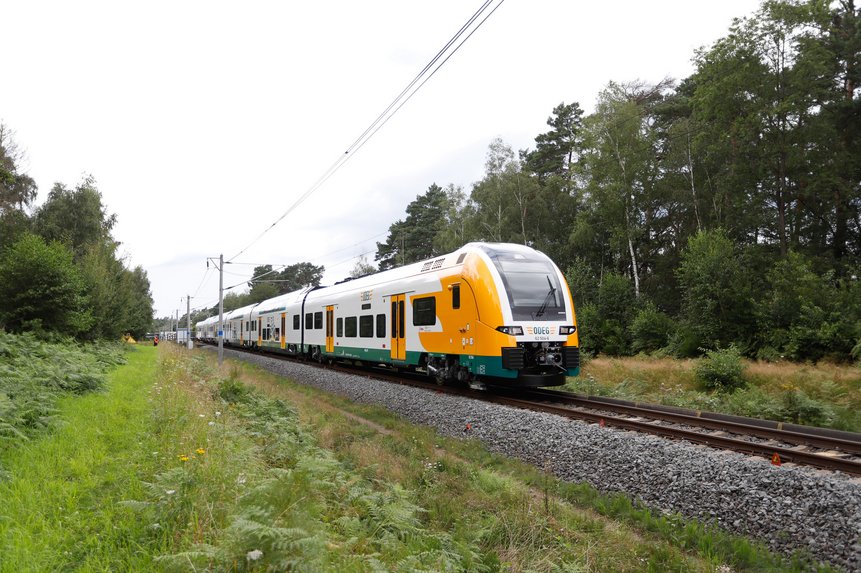 Das Foto zeigt den Desiro HC-Zug von außen auf einer Bahnstrecke durch die Natur.