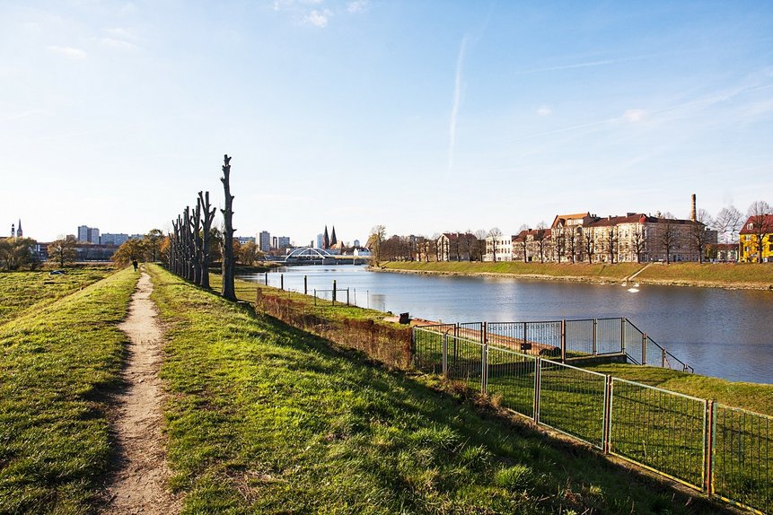 Ein Feldweg zur Halbinsel auf der Oder - auf der rechten Seite ist der Slubicer Hafen zu sehen und im Hintergrund die Grenzbrücke.