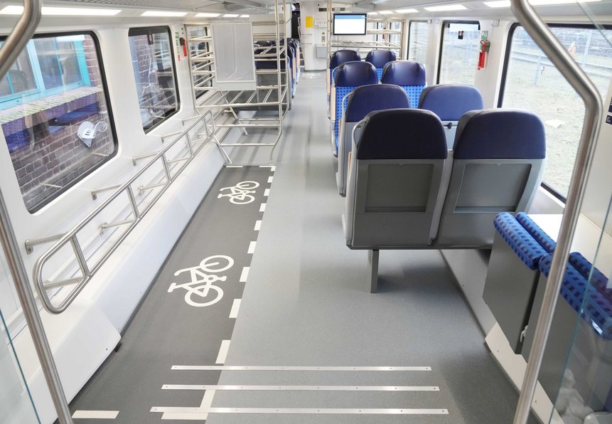 Das Foto zeigt das Unterdeck eines modernisierten Doppelstockwagens mit Fahrradabstellbereichen und Sitzplätzen.