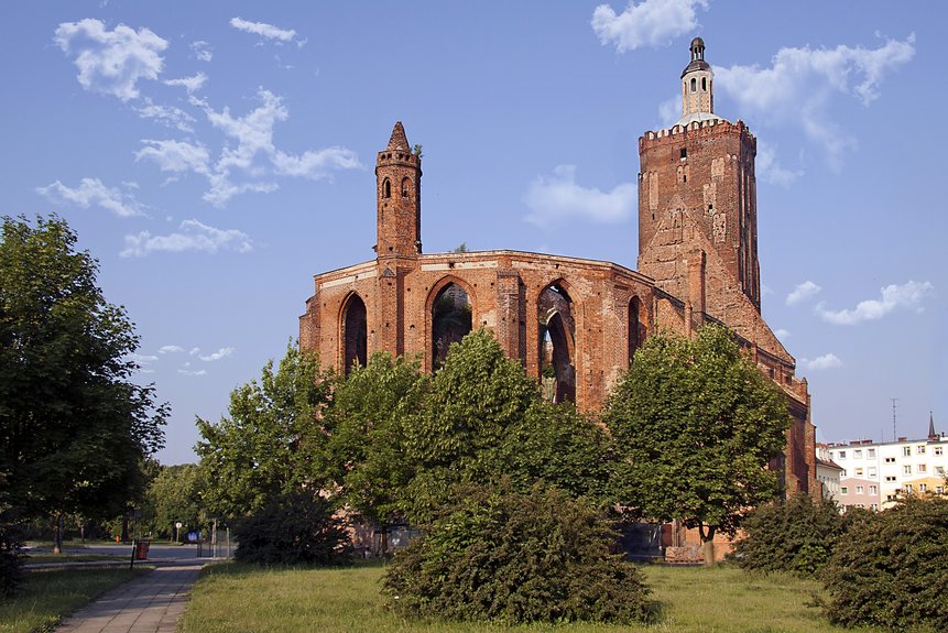 Ruinen der Pfarrkirche im Stadtzentrum Gubins mit grünen Bäumen im Vordergrund.
