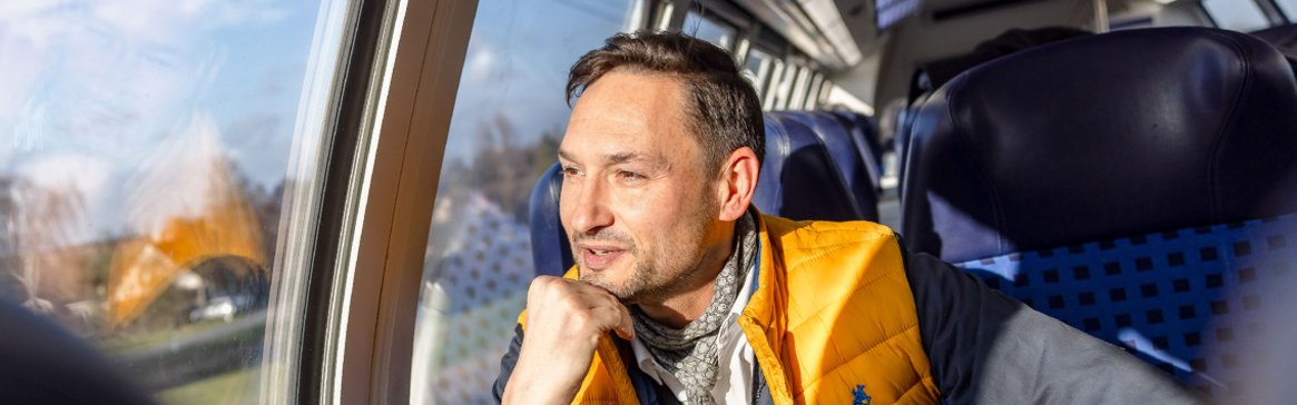 Mann in Regionalbahn am Fensterplatz