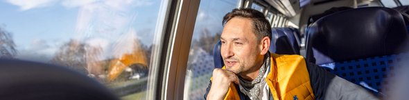 Mann in Regionalbahn am Fensterplatz